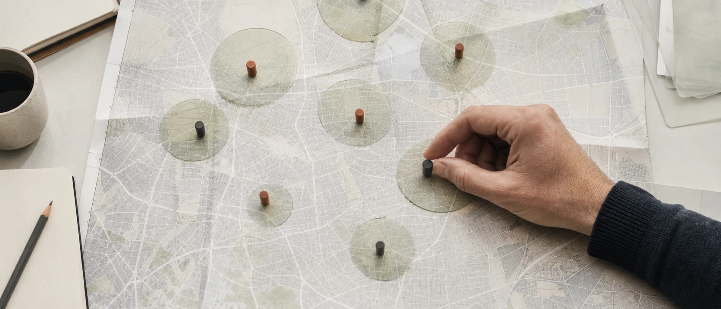 A hand placing search-result markers carefully across an unlabeled folded city map.